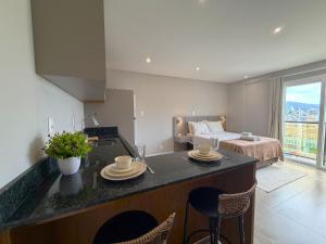 a kitchen with a counter with chairs and a bed at Sua estadia exclusiva em Blumenau a 350m da Vila Germânica - OCNs in Blumenau