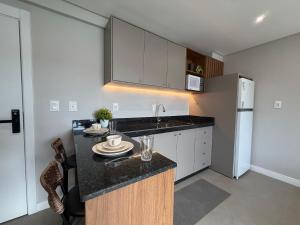a kitchen with a counter with a sink and a refrigerator at Sua estadia exclusiva em Blumenau a 350m da Vila Germânica - OCNs in Blumenau