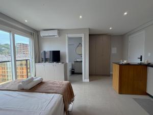 a bedroom with a bed and a kitchen and a sink at Sua estadia exclusiva em Blumenau a 350m da Vila Germânica - OCNs in Blumenau