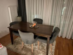 a wooden table with chairs and a bowl of fruit on it at Basca Lux apartman in Sarajevo