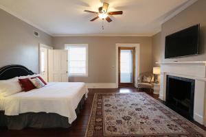 a bedroom with a bed with a ceiling fan and a fireplace at Oglethorpe Manor Main House in Savannah