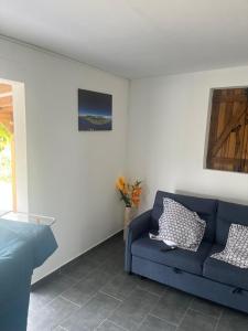 a living room with a blue couch and a window at Le gîte de Chris in Sainte-Anne