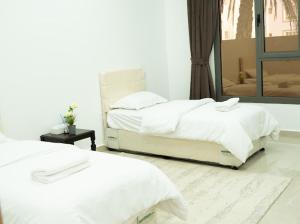 two white beds in a bedroom with a mirror at استراحة روضة الوادي - Rawdat Al Wadi House in Nizwa