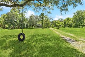 a tire swing hanging from a tree in a field at Nola Swamp Farm in Terrytown