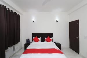 a bedroom with a large white bed with red pillows at Hotel O The Primero Near Leisure Valley Park in Gurgaon +15 photos