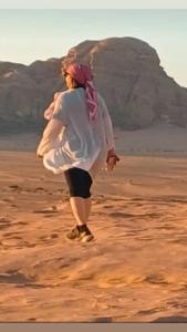 ワディ・ラムにあるRUM iSLAND bubble LUXURU CAMPの山を背景に砂漠を歩く女性