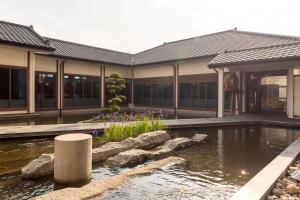 a house with a pond in front of a building at Sheraton Taoyuan Hotel in Dayuan