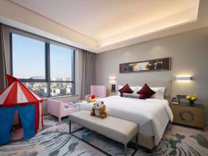 Un dormitorio con una cama grande con un osito de peluche sentado en un banco. en Grand Mercure Jinan Sunshine, en Jinan 139 fotos más