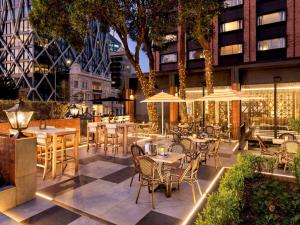 ein Restaurant mit Tischen, Stühlen und Sonnenschirmen in der Unterkunft Pullman Auckland Hotel & Apartments in Auckland