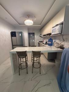 a kitchen with a white counter and two bar stools at Triplex Belém in Belém +8 photos