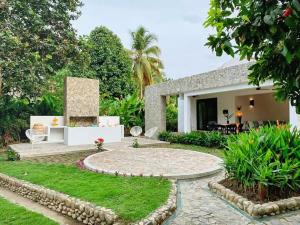 a garden with a patio and a house at Senda Beach House Tayrona in Santa Marta