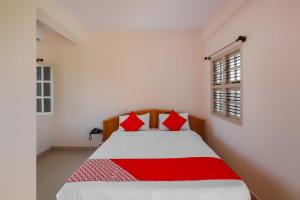 a bedroom with a bed with red pillows at Hotel O Narayani Residency in Mysore +17 photos