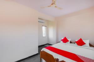 a bedroom with a large bed with red pillows at Hotel O Narayani Residency in Mysore