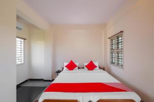 a red and white bed in a room with windows at Hotel O Narayani Residency in Mysore