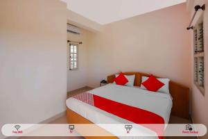 a bedroom with a bed with red pillows at Hotel O Narayani Residency in Mysore