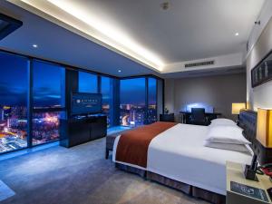 a hotel room with a large bed and a television at Pullman Guiyang in Guiyang +83 photos