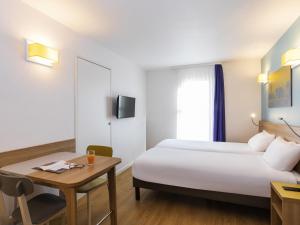 a hotel room with a large bed and a desk at Aparthotel Adagio Access La Défense - Place Charras in Courbevoie +38 photos