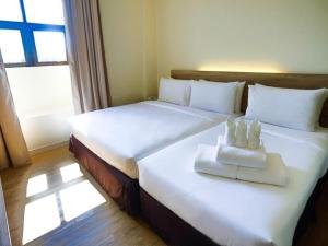 a large white bed with two white towels on it at Rooms By Rocana in Kuantan