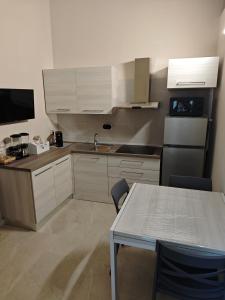 a kitchen with white cabinets and a table and a television at B&B Delle Rose in Orta Nova
