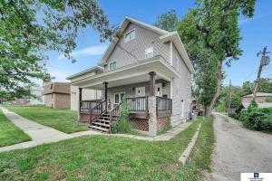a white house with a porch and a driveway at Modern and furnished apartment in downtown Lincoln in Lincoln