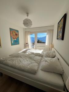 een groot bed in een slaapkamer met een raam bij Cozy apartment with stunning view in Anzère