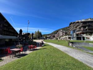 a park with red tables and chairs on the grass at Cozy apartment with stunning view in Anzère