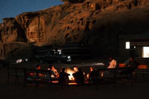 a group of people sitting around a fire at night at Fire bedouin camp in Wadi Rum