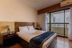 a bedroom with a large bed and a large window at Flats Hotel Paulista | Delfhy in São Paulo