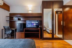 a room with a television and a desk with a chair at Flats Hotel Paulista | Delfhy in São Paulo