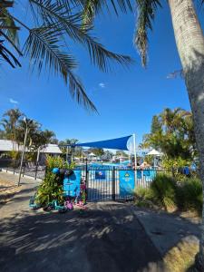 a pool with a gate and palm trees at Tuncurry 2BR Walk to Lake in Tuncurry