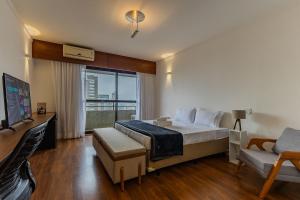 a bedroom with a bed and a tv and a couch at Flats Hotel Paulista | Delfhy in São Paulo