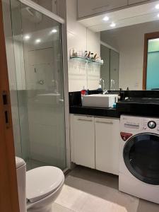 a bathroom with a toilet and a sink and a washing machine at Complet apartment with air conditioning in Belém