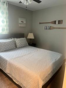 a bedroom with a white bed and a ceiling fan at Midtermlongterm Buckroe Beach Bungalow Ev Chrg in Hampton