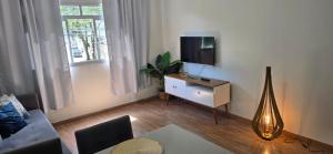 un soggiorno con una TV, un divano e un tavolo di Dois quartos espaçoso a Vitória