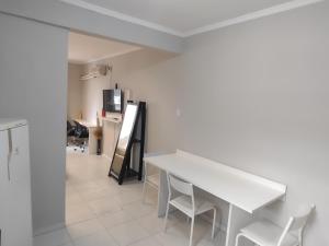 a white dining room with a white table and chairs at Apto Studio 202 centro floripa in Florianópolis +12 photos