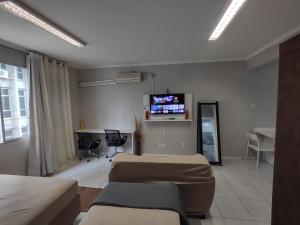 a room with two beds and a tv on the wall at Apto Studio 202 centro floripa in Florianópolis
