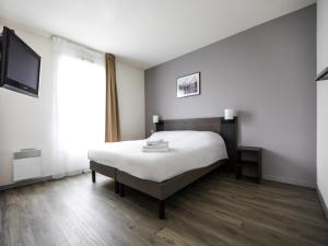 a bedroom with a bed and a large window at Aparthotel Adagio Access Orléans in Orléans
