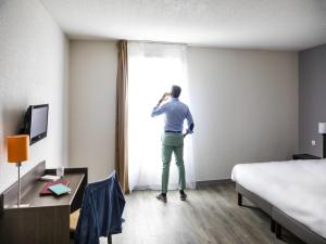 a man looking out of a window in a hotel room at Aparthotel Adagio Access Orléans in Orléans +46 photos