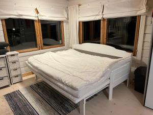 a white bed in a room with windows at Cottage on the shore of Ivalojoki in Inari