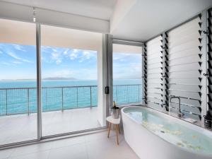 a bathtub in a bathroom with a view of the ocean at Grand Mercure Apartments Magnetic Island in Nelly Bay +130 photos