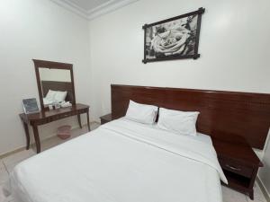 a bedroom with a bed with a wooden headboard and a mirror at شقق أماسي الواحة بالعقيق in Al ‘Aqīq