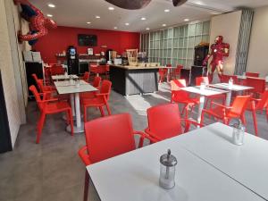 a restaurant with red chairs and tables and a red wall at Ibis Styles Paris Saint Denis La Plaine in Saint-Denis