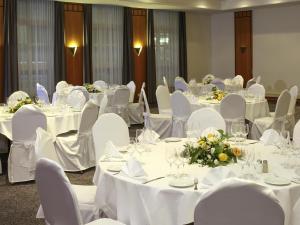 Un salón de banquetes con mesas y sillas blancas. en ibis Styles Luzern, en Lucerna