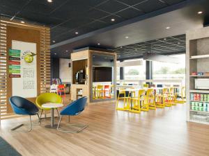 a restaurant with yellow and blue chairs and tables at ibis budget Hotel Edinburgh Park in Edinburgh