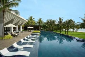 une rangée de chaises longues blanches à côté d'une piscine dans l'établissement JW Marriott Cam Ranh Bay Resort & Spa, à Cam Ranh