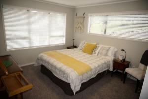 une chambre avec un lit, une chaise et des fenêtres dans l'établissement House close to Oneroa Village, beach, and wineries, à Waiheke Island