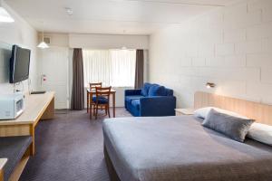 um quarto de hotel com uma cama, uma mesa e uma cadeira em Box Hill Motel em Burwood