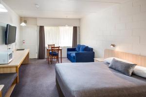 a hotel room with a bed and a table and a chair at Box Hill Motel in Burwood