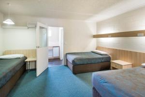 a hotel room with two beds and a doorway at Box Hill Motel in Burwood