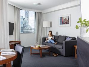 a woman sitting on a couch in a living room at The Sebel Brisbane in Brisbane